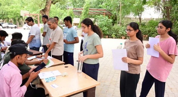 गुरुग्राम में नीट यूजी परीक्षा केंद्र में प्रवेश से पूर्व परीक्षार्थियों की जांच करते स्टाफ।