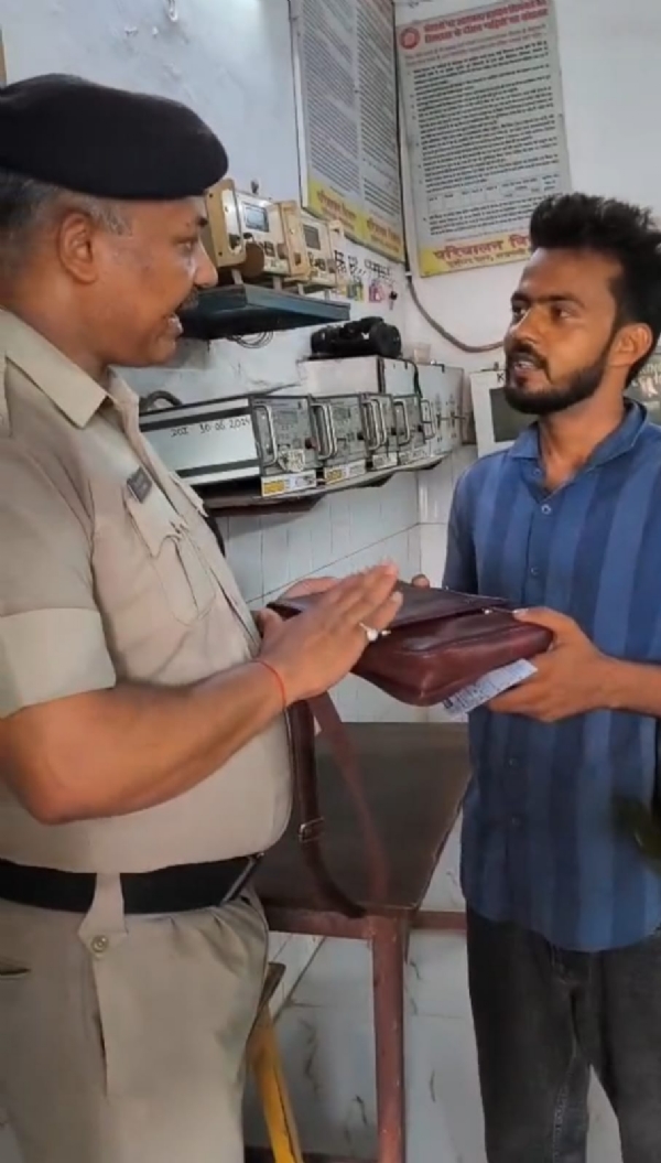 यात्री को रुपयों से भरा बैग सुपुर्द करते आरपीएफ अधिकारी
