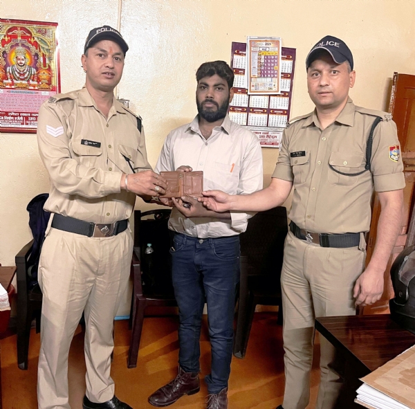 श्रद्धालु को उसका खोया पर्स खोजकर वापस लौटाते पुलिस कर्मी।