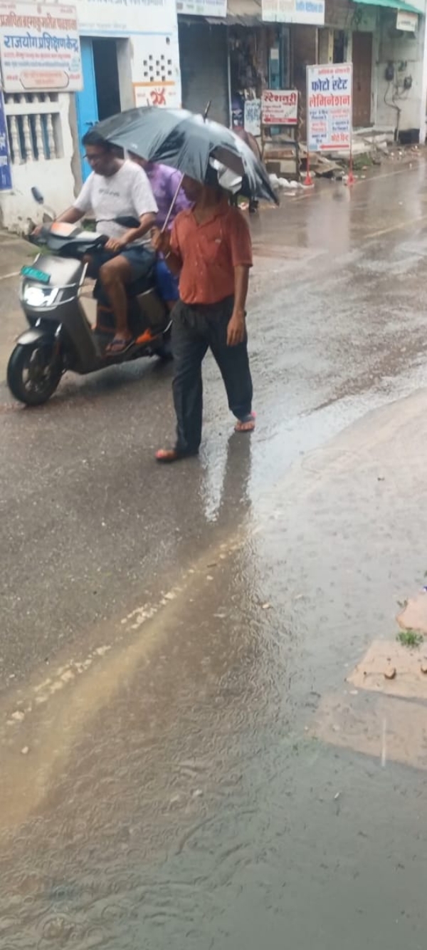 बारिश के कारण सड़कों पर छाता लेकर जाते हुए लोग